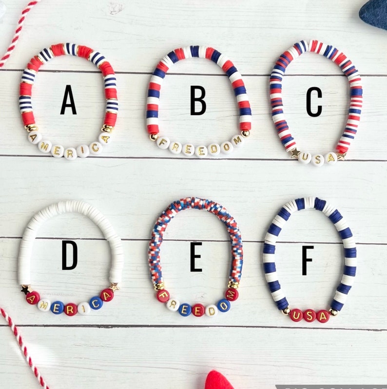 K&ouml;nnte beinhalten: Sechs Armb&auml;nder mit roten, wei&szlig;en und blauen Perlen. Die Armb&auml;nder buchstabieren "America", "Freedom", "USA", "America", "Freedom" und "USA".