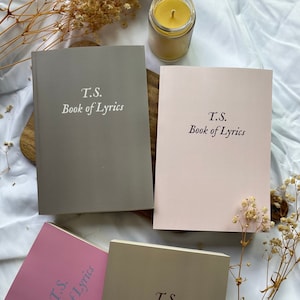 May include: Four gray, pink, and beige notebooks with the text "T.S. Book of Lyrics" printed on the front.