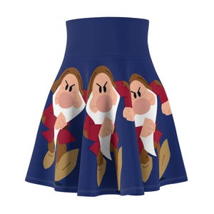 Puede incluir: Una falda skater azul marino con un patrón repetido de personajes de dibujos animados. Los personajes tienen cabello castaño, narices grandes y barbas blancas, con chaquetas rojas y zapatos marrones. La falda tiene un diseño de cintura alta.