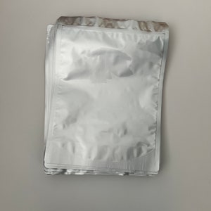 May include: A stack of clear, silver, and white plastic resealable bags with a zipper closure.