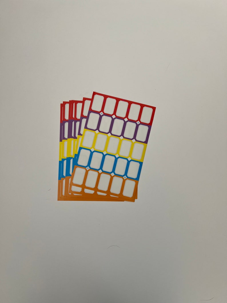 May include: A stack of four sheets of colorful sticker labels. Each sheet has a grid of 20 white rectangular labels with a black border. The sheets are red, purple, yellow, and blue.