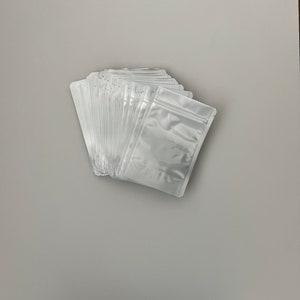 May include: A stack of white plastic resealable bags with a zipper closure.