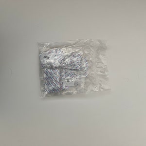 May include: A clear plastic bag containing several small white packets with blue and red text. The text on the packets reads "4002C".