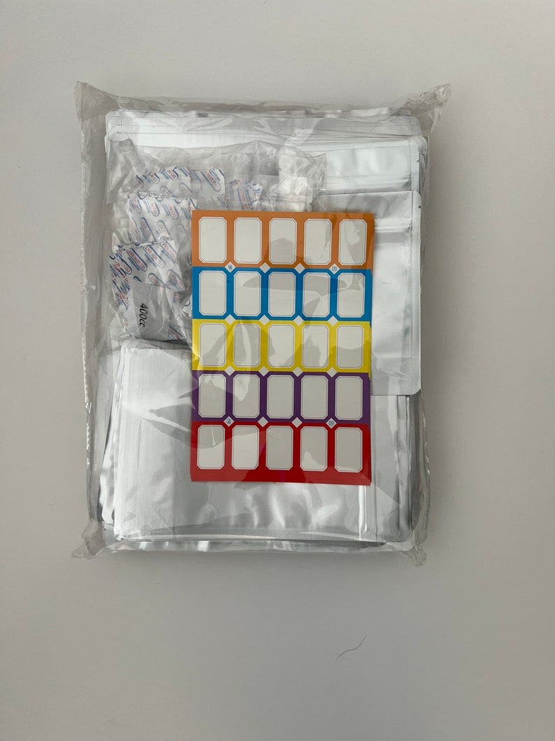 May include: A clear plastic bag filled with a large quantity of clear plastic bags with a label sheet featuring four rows of blank labels in orange, blue, yellow, and purple.
