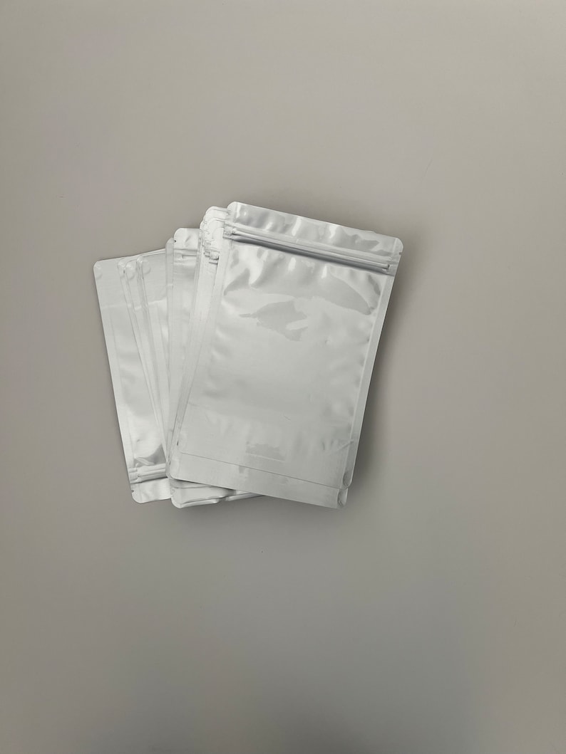 May include: A stack of five white plastic resealable bags with a zipper closure.