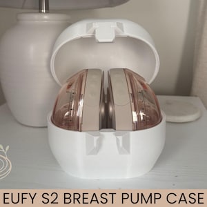 May include: A white Eufy S2 breast pump case with a hinged lid, containing two wearable breast pump units. The pump units are beige and translucent pink with visible measurement markings on the sides and control buttons on the top surface.