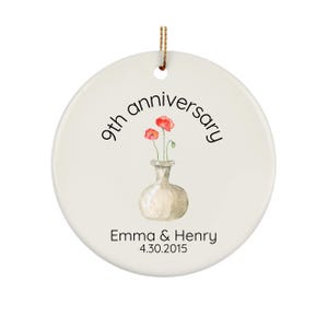 May include: White ceramic ornament with a 9th anniversary message, red poppy flowers in a vase, and the names Emma & Henry with the date 4.30.2015.
