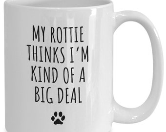 May include: White ceramic coffee mug with black text that reads "My Rottie thinks I'm kind of a big deal" and a black paw print.