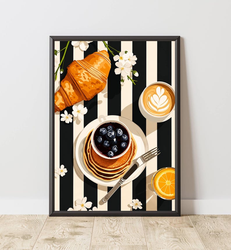 Pu&ograve; includere: Una stampa artistica incorniciata raffigurante una scena di colazione con un croissant dorato, una pila di pancake guarniti con mirtilli in una ciotolina, un latte macchiato con decorazione in schiuma e un bicchiere di succo d'arancia su sfondo a righe.