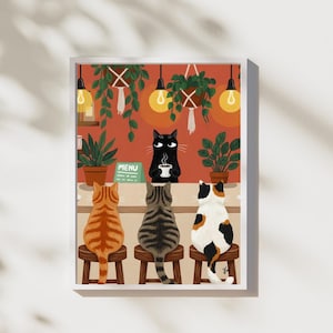 Puede incluir: Una impresión artística enmarcada representa una escena de cafetería para gatos. Tres gatos están sentados en un mostrador, mientras que un gato negro sirve café. El fondo presenta plantas colgantes, bombillas y un letrero de menú. La paleta de colores incluye naranja, marrón y verde.