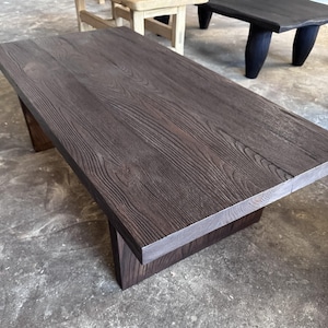 Può includere: Un tavolino rettangolare in legno marrone scuro con una texture di venature del legno visibile. Il tavolo ha un piano spesso e una base solida. Il tavolo misura circa 122 cm di lunghezza e 61 cm di larghezza.