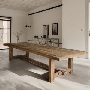 Könnte beinhalten: Ein großer, rechteckiger Esstisch aus Holz mit natürlicher Oberfläche. Der Tisch hat dicke Beine und eine stabile Basis. Der Tisch ist etwa 305 cm lang und 102 cm breit.