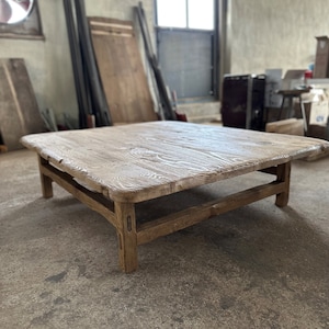 May include: A rustic wooden coffee table with a rectangular top and a simple, sturdy frame. The table is made of reclaimed wood and has a natural, weathered finish.