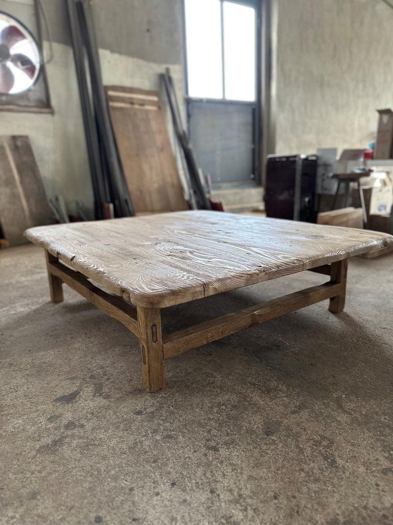 May include: A rustic wooden coffee table with a rectangular top and a simple, sturdy frame. The table is made of reclaimed wood and has a natural, weathered finish.