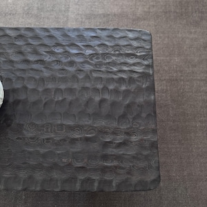 Op de afbeelding: Een donkerbruine houten salontafel met een getextureerd oppervlak. De tafel heeft een rechthoekige vorm en een gladde, gepolijste afwerking.