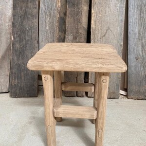 May include: A rustic wooden side table with a square top and a lower shelf. The table is made of natural wood with a light brown finish and has a simple, handcrafted design.