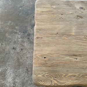 May include: Close-up of a light brown wooden table top with a natural wood grain pattern. The surface is smooth and has a few knots and imperfections.