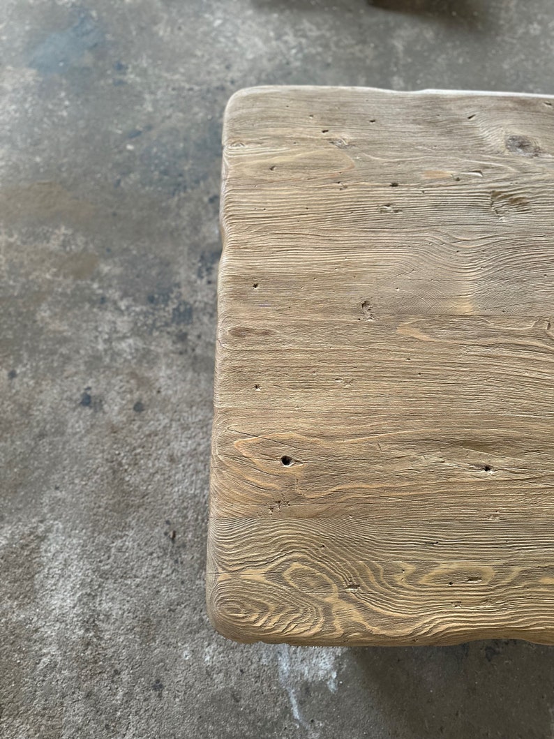 May include: Close-up of a light brown wooden table top with a natural wood grain pattern. The surface is smooth and has a few knots and imperfections.