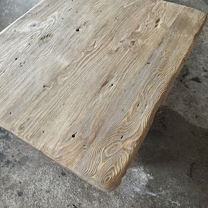 May include: A rustic wooden coffee table with a natural wood finish and a rectangular shape. The table has a distressed look with knots and grain patterns visible in the wood.
