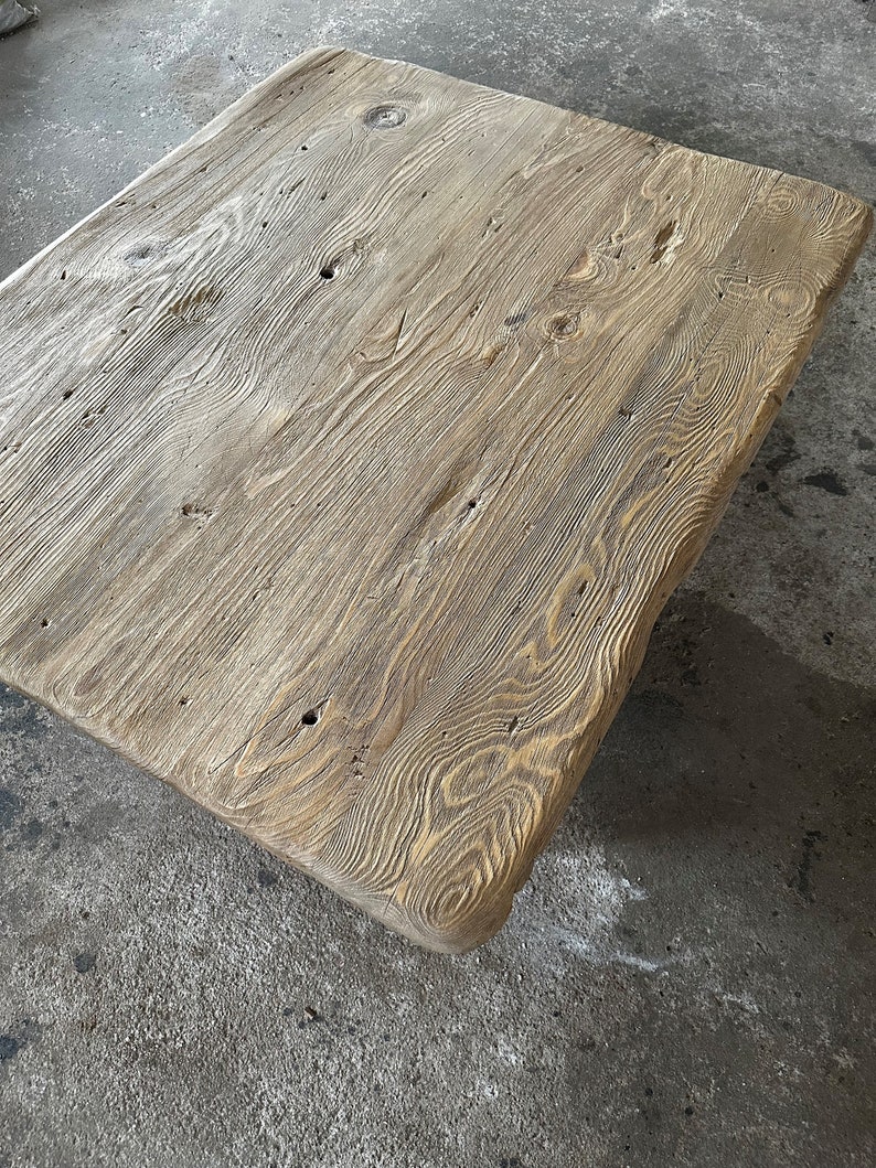 May include: A rustic wooden coffee table with a natural wood finish and a rectangular shape. The table has a distressed look with knots and grain patterns visible in the wood.