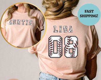 Pode incluir: Uma camiseta rosa com um design de beisebol. A camiseta tem o texto "LISA 08" nas costas, com o número 08 dentro de um gráfico de beisebol. A camiseta também tem o texto "AUNTIE" na frente.