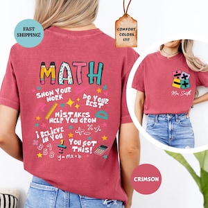 Puede incluir: Camiseta de color carmes&iacute; con un dise&ntilde;o tem&aacute;tico de matem&aacute;ticas. El dise&ntilde;o incluye la palabra "MATH" en letras coloridas, junto con frases como "Show Your Work" y s&iacute;mbolos matem&aacute;ticos. Una etiqueta dice "Comfort Colors 1717".