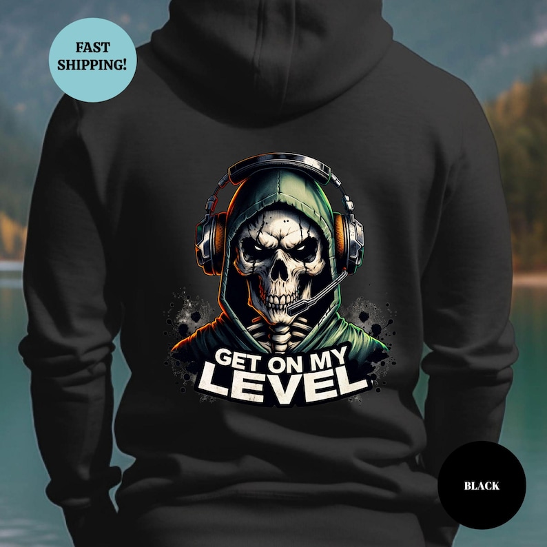 May include: Black hoodie featuring a skull wearing a headset and a green hood. The graphic includes the text "GET ON MY LEVEL" in white. The hoodie is a solid black color.