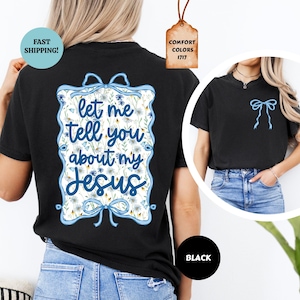 May include: Black t-shirt with a blue floral design and the text "let me tell you about my Jesus". The design includes a blue bow and floral accents. A smaller version of the bow is on the front of the shirt. The shirt is black.