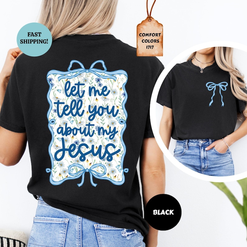 May include: Black t-shirt with a blue floral design and the text "let me tell you about my Jesus". The design includes a blue bow and floral accents. A smaller version of the bow is on the front of the shirt. The shirt is black.