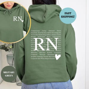 May include: A military green hoodie with a white 'RN' and a heart on the front. The back of the hoodie has a list of positive words describing a registered nurse.