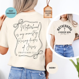 May include: A white t-shirt with a black graphic that says "Motherhood is my ministry Raising disciples of Jesus Proverbs 22:6". The shirt is shown on a model wearing blue jeans.