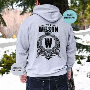 May include: A gray hooded sweatshirt with the text "It's a Wilson thing" and a black and white graphic of a "W" inside a wreath. The text "You wouldn't understand" is below the graphic.