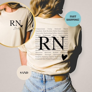 May include: A white t-shirt with the letters "RN" and the word "Endey" printed on the front. The back of the shirt has the letters "RN" printed in large font with a list of positive adjectives surrounding the letters. The adjectives include words like compassionate, caring, dedicated, patient, empathetic, kind, resilient, skilled, knowledgeable, trustworthy, hardworking, selfless, attentive, gentle, reliable, professional, brave, understanding, resourceful, passionate, calm, thoughtful, committed, relevant, tenacious, intelligent, wise, efficient, strong, flexible, honest, authentic, adaptable, inspirational, friendly, honest, practical, humble, approachable, conscientious, generous, meticulous, motivated, realistic, courageous, competent, thorough, determined, helpful, insightful, nurturing, cheerful, motivating, composed, alert, warm, diligent, and focused.