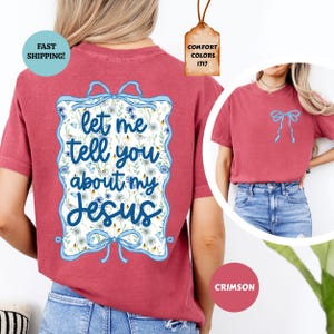 May include: Crimson-colored t-shirts with the text "Let me tell you about my Jesus" in a blue floral design. The shirt also features a small blue bow on the front. The shirt is a comfort color.