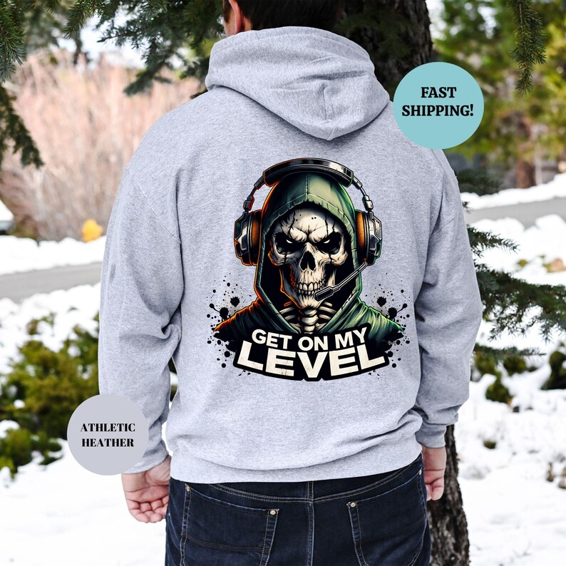 May include: Athletic heather gray hoodie with a graphic of a skull wearing a headset and a green hood. The text "GET ON MY LEVEL" is below the skull. The hoodie is shown from the back.