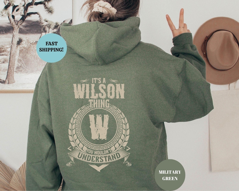 May include: A green hooded sweatshirt with the text "It's a Wilson Thing You Wouldn't Understand" and a stylized "W" in a circle. The sweatshirt is a military green color.