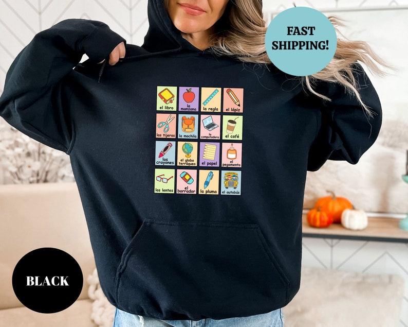 May include: Black hoodie with a graphic of a grid of colorful squares featuring Spanish words and illustrations of school supplies. The text "FAST SHIPPING!" is in a blue circle at the top right corner of the image.