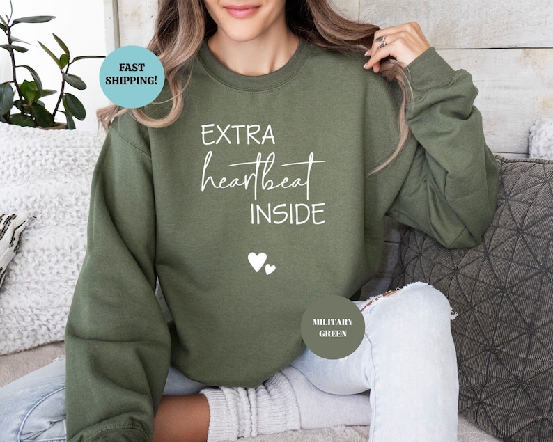 Pode incluir: Uma camisa de moletom verde com o texto "EXTRA heartbeat INSIDE" em letras brancas e dois &iacute;cones de cora&ccedil;&atilde;o brancos.