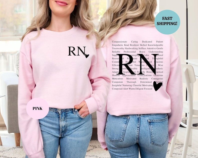 May include: Pink sweatshirt with the letters "RN" and a heart on the front. The back of the sweatshirt has the letters "RN" in a large font surrounded by a word cloud of positive adjectives describing a nurse.