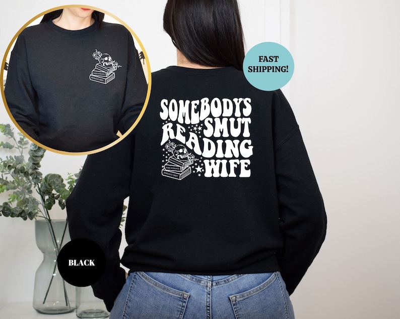 May include: Black sweatshirt with a white graphic on the back that says "Somebody's Smut Reading Wife" with a skull and books. The front of the sweatshirt has a small graphic of a skull and books.