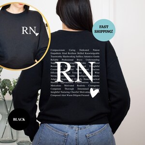 May include: Black sweatshirt with a white 'RN' with a heart on the front and a list of positive adjectives describing a registered nurse on the back.