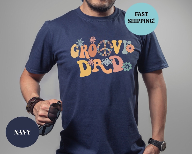 May include: A navy blue t-shirt with a retro-style graphic that says "Groovy Dad" in colorful letters surrounded by flowers.