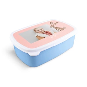 May include: A rectangular lunchbox in light blue with a white lid. The lid has a pink border with a photo of a child and a brown rabbit illustration. The child's name, Sophia, is written in cursive.