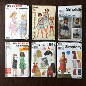 May include: Six vintage Simplicity sewing patterns for children's clothing. The patterns feature a variety of styles, including dresses, skirts, and pants. The patterns are all in good condition and have been well-loved.