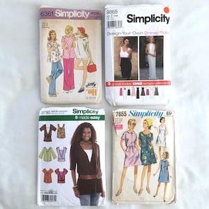 May include: Four Simplicity sewing pattern envelopes with different designs. The patterns include a dress, a robe, a top, and a tunic. The patterns are all in different colors and styles.