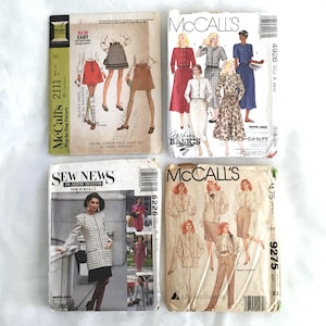 May include: Four vintage sewing patterns for women's clothing. The patterns are from McCall's and feature different styles of skirts, jackets, and blouses. The patterns are in various colors, including white, black, brown, and blue. The patterns are labeled with the numbers 2111, 4926, 6226, and 9275.
