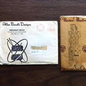 May include: A vintage envelope with a black and white illustration of yarn and knitting needles. The envelope is addressed to Alice Brooks Designs Needlecraft Service. The envelope has a stamp and a handwritten number "7008". A vintage pattern envelope with a woman wearing a dress and the text "Marian Martin Pattern and Sew-Chart".