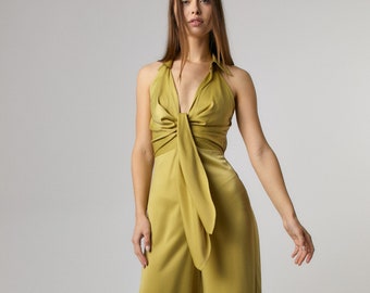 Könnte beinhalten: Ein senfgelber Satin-Jumpsuit mit einem Halterneck und einem Knotendetail am Busen. Der Jumpsuit hat weite Beine und eine lockere Passform.