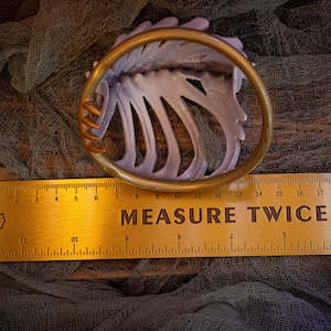 Measurement of the bun cover showing the underside and hooks (~10cm in length)
