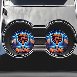 May include: Two car coasters featuring the Chicago Bears logo. The coasters have a blue background with a cityscape and lightning bolts. The team's orange bear head logo is centered above the text "Chicago Bears".
